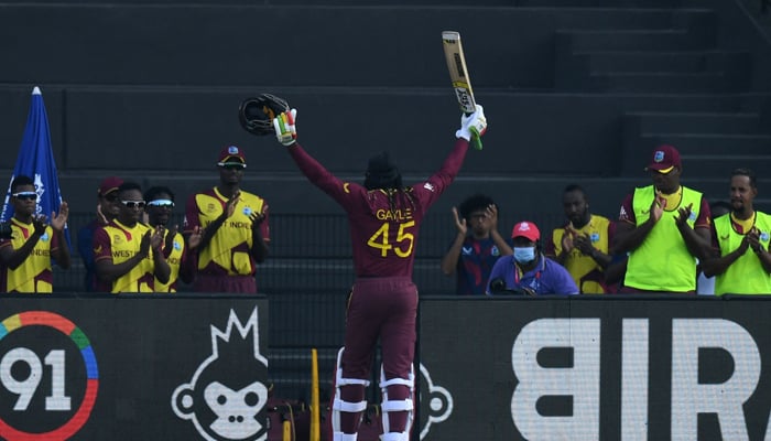 West Indies´ Chris Gayle (C) raises his hands as he is being greeted by his teammates after his dismissal during the ICC Twenty20 World Cup cricket match between Australia and West Indies at the Sheikh Zayed Cricket Stadium in Abu Dhabi on November 6, 2021. — AFP