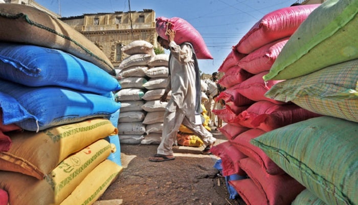 In this file photo, a Pakistani laborer carries a bag of sugar through a market in Karachi. Photo: AFP