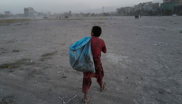 Eftekhar, 14, membawa tas berisi botol plastik yang dikumpulkannya, untuk dijual, saat dia berjalan di taman bermain di Kabul, Afghanistan, 22 Oktober 2021. Foto: Reuters
