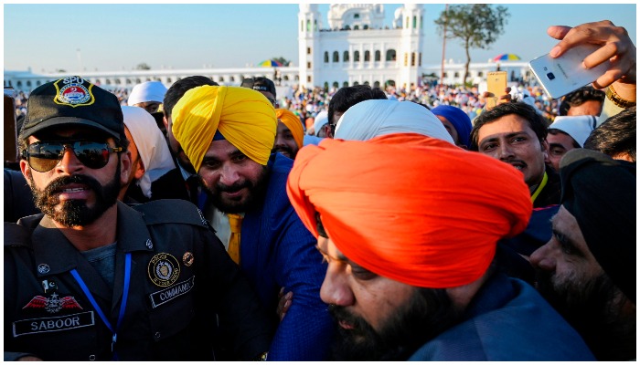 Personel keamanan mengawal politisi India dan mantan pemain kriket Navjot Singh Sidhu saat ia mengunjungi Kuil Baba Guru Nanak Dev di Gurdwara Darbar Sahib di Kartarpur, dekat perbatasan India, pada 9 November 2019. Foto: AFP