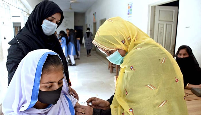 A health worker administering a coronavirus vaccine to students at Government Girls Little Folks Higher Secondary School in Larkana, Sindh, on October 27, 2021. Photo: APP