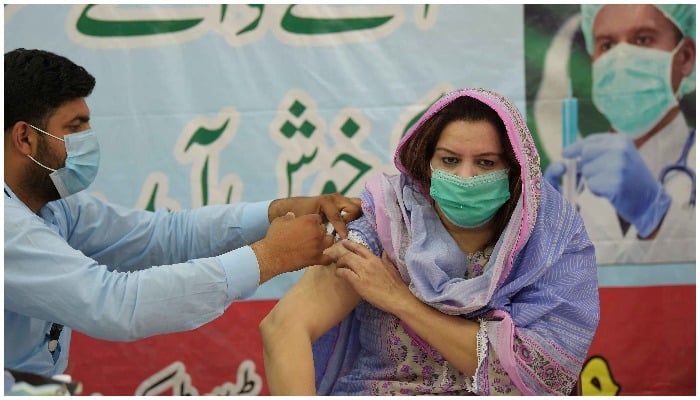 Seorang petugas kesehatan memberikan vaksin COVID-19 kepada seorang wanita di Rawalpindi pada 25 Mei. — AFP
