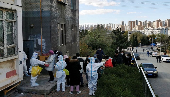 Orang-orang berbaris untuk pengujian asam nukleat di kompleks perumahan menyusul kasus lokal penyakit virus corona (COVID-19) di Dalian, provinsi Liaoning, China 10 November 2021. Foto: China Daily via Reuters