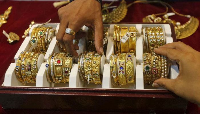 Seorang penjual membantu pelanggan (kanan) memilih gelang emas di ruang pamer perhiasan di Mumbai, India, 21 Mei 2015. Reuters/File