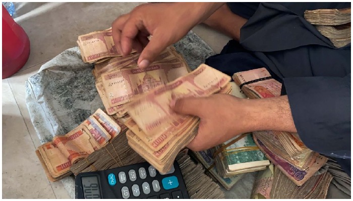 Orang yang memegang tumpukan uang kertas — AFP
