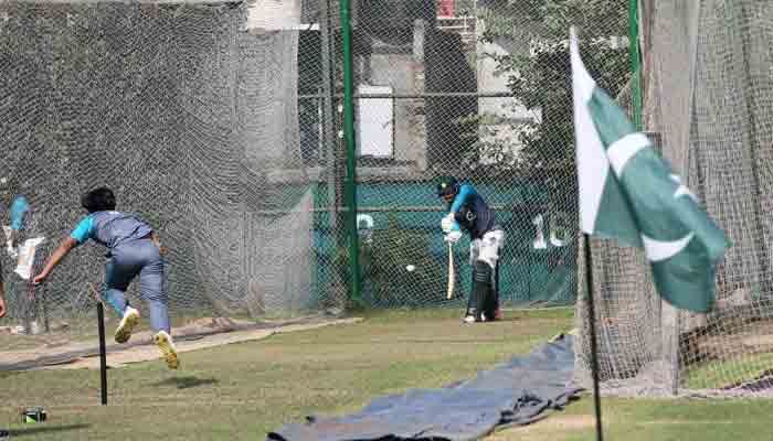 Pakistan cricketers during a practice session with the national flag in the foreground. Photo: File.
