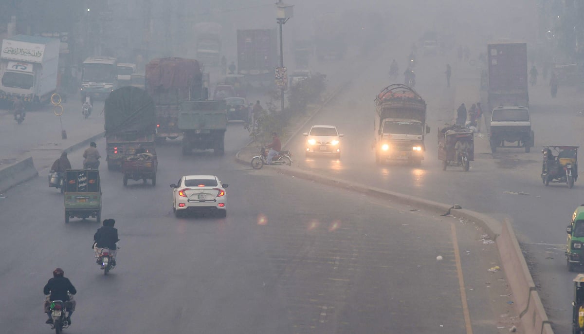 People commute along a street amid heavy smoggy conditions in Lahore on November 18, 2021. — AFP
