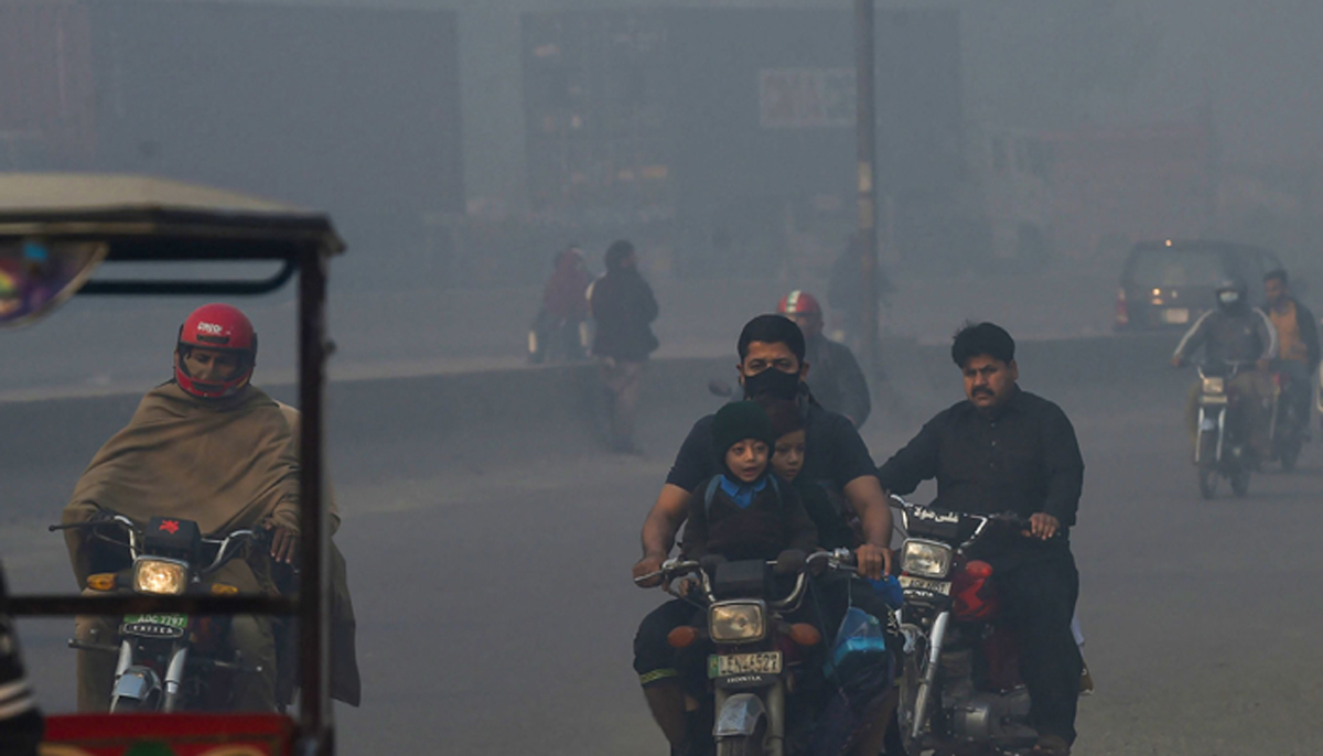 Orang-orang bepergian di sepanjang jalan di tengah kondisi kabut asap tebal di Lahore pada 18 November 2021. — AFP