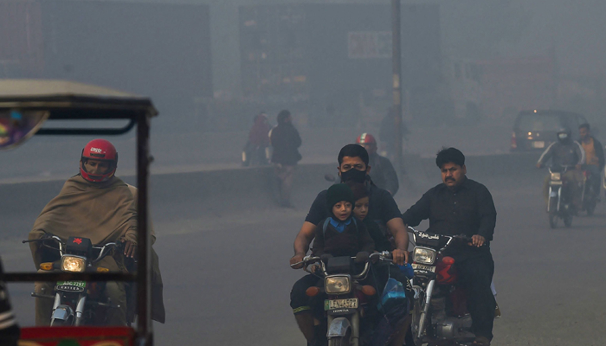 People commute along a street amid heavy smoggy conditions in Lahore on November 18, 2021. — AFP