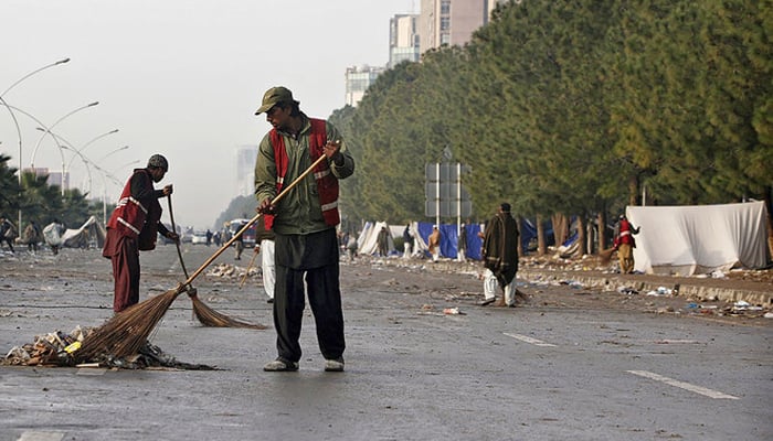 Cleaners sweep a street in Islamabad. — Reuters