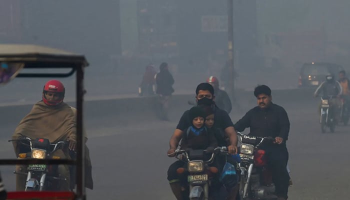 Orang-orang bepergian di sepanjang jalan di tengah kondisi kabut asap tebal di Lahore pada 18 November 2021. — AFP/File