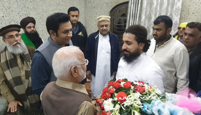 PTI Senator Ejaz Chaudhry (left) handing over a bouquet to Tehreek-e-Labbaik Pakistan (TLP) chief Maulana Saad Rizvi (right) in Lahore on November 20, 2021. — Twitter