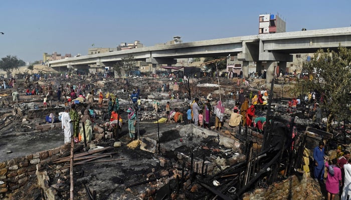 Residents search for their belongings amid debris of their burnt houses after a fire broke out in a slum area in Karachi on November 20, 2021. — AFP