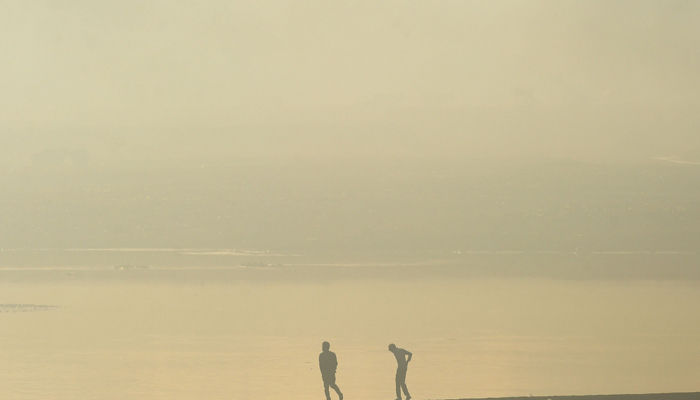 People walk along the banks of river Ravi amid smoggy conditions in Lahore on November 22, 2021. — AFP