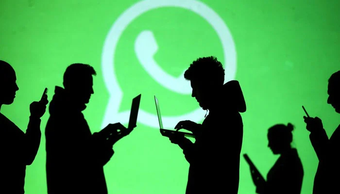 Silhouettes of laptop and mobile device users are seen next to a screen projection of WhatsApp logo in this picture illustration taken March 28, 2018. — Reuters/File