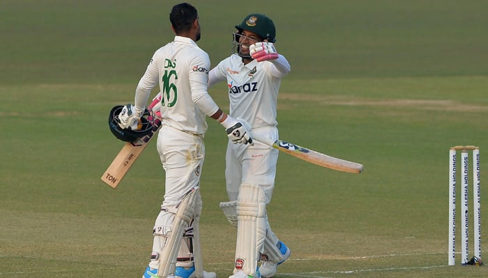 Bangladeshs Liton Das (L) is congratulated by teammate Mushfiqur Rahim after he scored a century (100 runs) during the first day of the first Test cricket match between Bangladesh and Pakistan at the Zahur Ahmed Chowdhury Stadium in Chittagong on November 26, 2021۔ —AFP