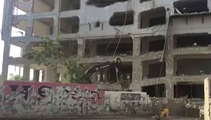 A bulldozer works on Karachis Nasla Tower. Photo: Geo News screengrab