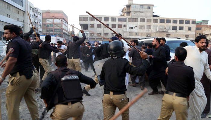 Men run as law enforcement agencies charge batons and on protesters at Nasla Tower in Karachi on November 26, 2021. — PPI