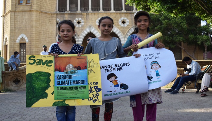 Tiga bersaudara, berusia 11, 13, dan 13 tahun (dari kiri), memegang poster bertuliskan Perubahan dimulai dari saya dan poster resmi acara di Climate March Karachi di Frere Hall di Karachi, Pakistan, 20 September 2019. Foto: Geo.tv/ mengajukan