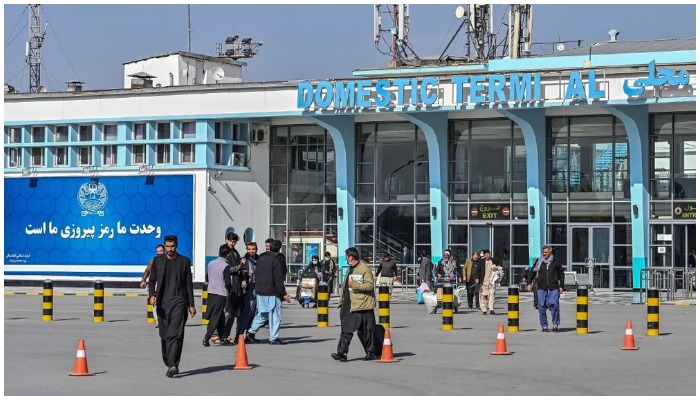 Afghan people walk near the exit gate of the Kabul airport in Kabul, Afghanistan, on November 24, 2021. AFP