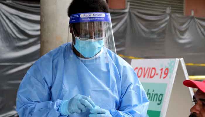 A doctor, wearing a mask and a face shield, administers a COVID-19 vaccine dose. Photo: Andrew Kutan/ AFP