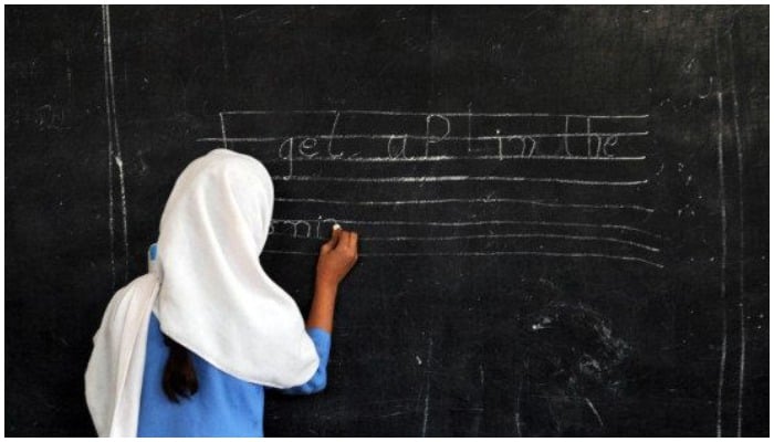 A Pakistani female student writes a sentence on a black board at a government school in Peshawar. Photo: AFP