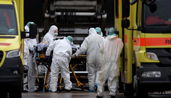 Medics wearing PPE transfer patients infected with the coronavirus (COVID-19) into the Airbus A310-900 MRTT MedEvac Hermann Koehl of the German armed forces Bundeswehr before they are airlifted and transported to other intensive care units (ICU) in the country, at Dresden International Airport, Saxony, eastern Germany on December 1, 2021۔ — AFP