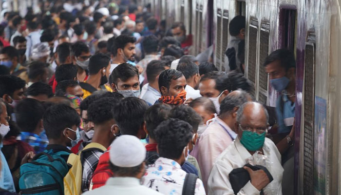 Komuter turun dari kereta pinggiran kota di stasiun kereta api, di tengah pandemi penyakit coronavirus (COVID-19), di Mumbai, India, 1 Desember 2021. Foto: Reuters