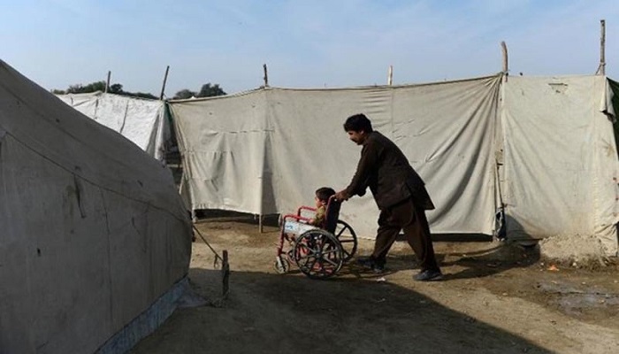 A man pushes the wheelchair of a disabled child. Photo: AFP