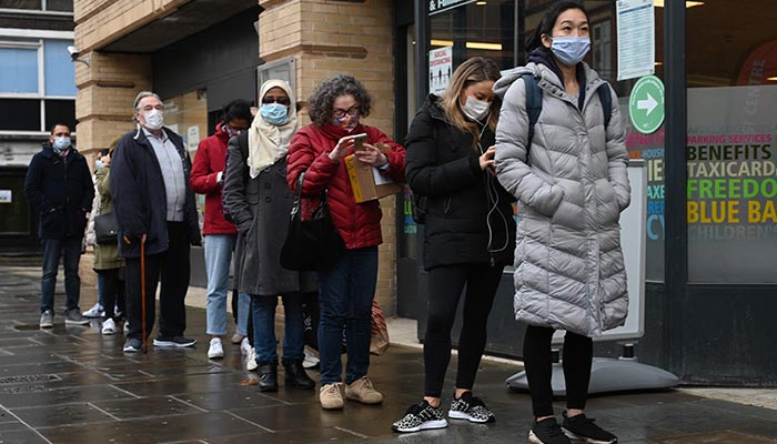 People wait in a queue outside a pop-up vaccination centre for the Covid-19 vaccine or booster, in Hammersmith and Fulham in Greater London on December 3, 2021. — AFP
