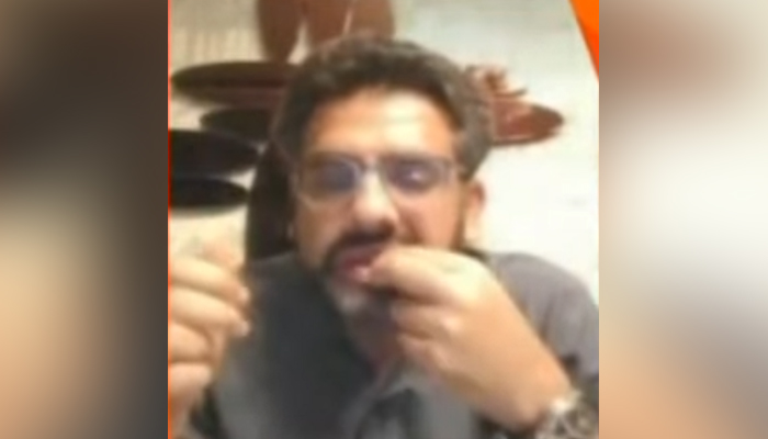 Finance ministry spokesperson Muzzammil Aslam munching on what appears to be some nuts, during an appearance on Geo News programme Naya Pakistan, on December 3, 2021. — Geo News