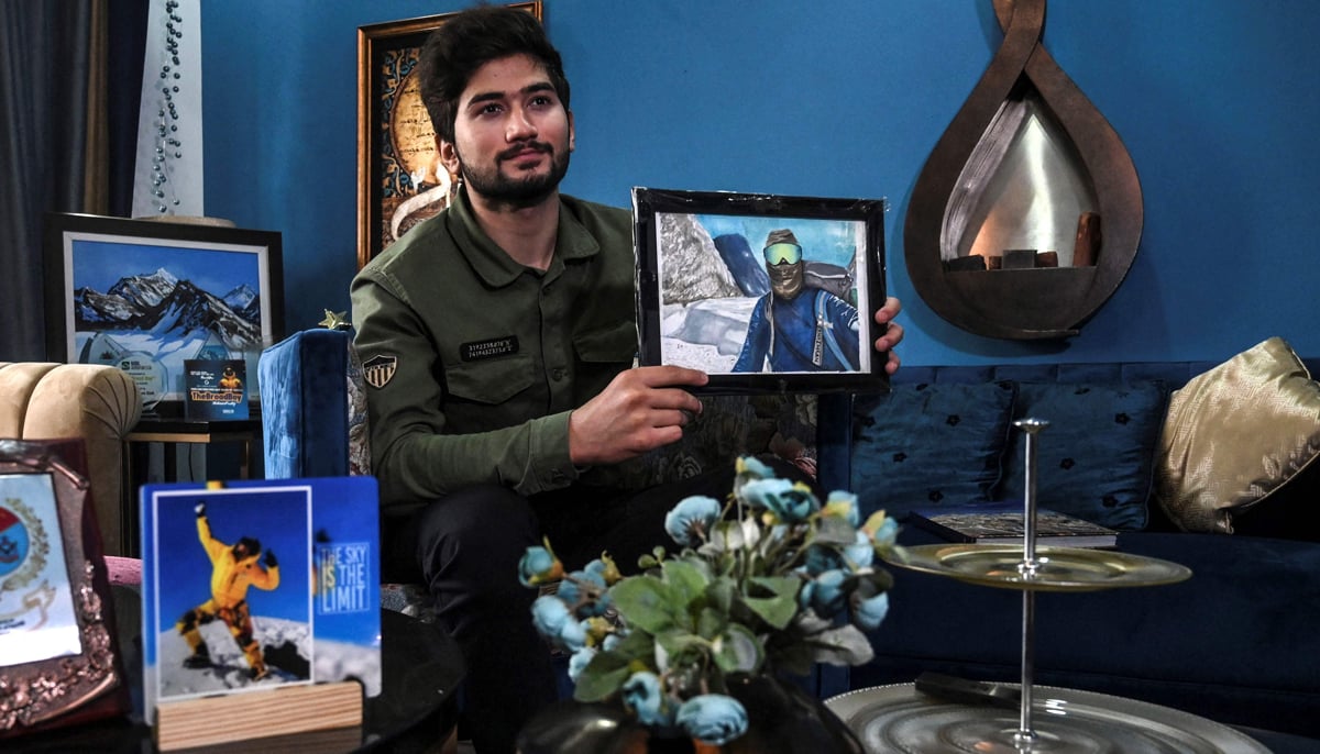 This picture taken on November 16, 2021 shows Pakistani mountaineer Shehroze Kashif holding a painting of himself, during an interview with AFP at his home in Lahore. — AFP