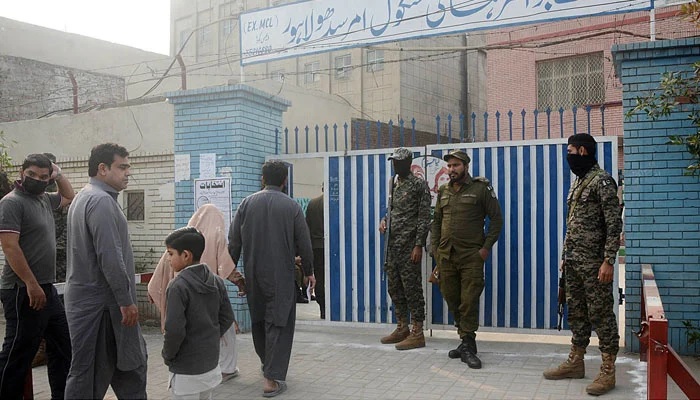 Security officials standing alert outside a polling station to avoid any untoward situation during by-elections of the NA-133 constituency, in Lahore, on December 5, 2021. Photo: APP