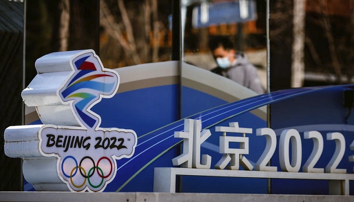 A man is reflected in a mirror as he walks past the logo of the Beijing 2022 Olympics in Beijing, China, November 30, 2021. Picture taken November 30, 2021. Photo: Reuters