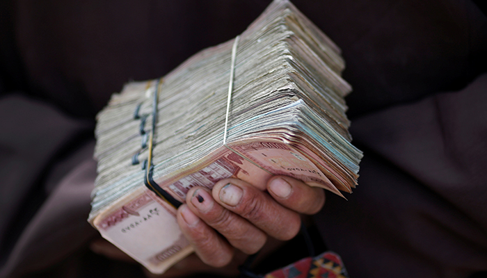 A money changer holds a stack of Afghan currency on a street in central Kabul April 2, 2014. — Reuters/File