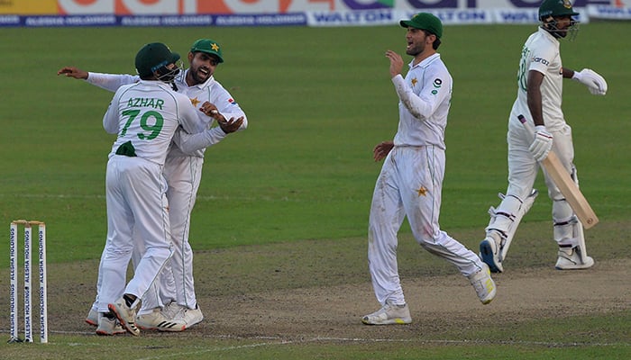 Pakistans Azhar Ali (L) celebrates their winning the match with captain Babar Azam (2L) as Bangladeshs Ebadot Hossain (R) walks off the field on the the final day of the second Test cricket match between Bangladesh and Pakistan at the Sher-e-Bangla National Cricket Stadium in Dhaka on December 8, 2021. — AFP