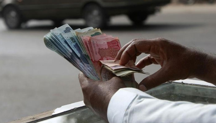 A money changer counts Pakistani Rupee (PKR) notes in Karachi September 23, 2009. — Reuters/File