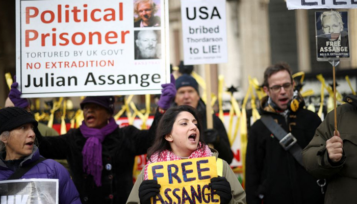 Supporters of Julian Assange hold signs outside the Royal Courts of Justice in London, Britain December 10, 2021. — Reuters