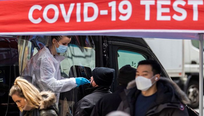 A man is tested for the coronavirus disease (COVID-19) at a mobile COVID-19 testing unit, as pedestrians make their way in the sidewalk during the spread of the Omicron coronavirus variant in Manhattan, New York, U.S., December 8, 2021. Photo: Reuters