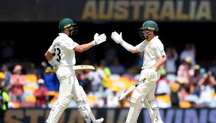 Australias Marnus Labuschagne (L) and teammate Marcus Harris celebrate after Australia won the first Ashes cricket Test match against England on day four at the Gabba in Brisbane on December 11, 2021. -AFP