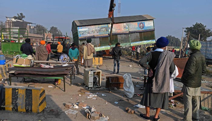 Farmers use a crane to dismantle a makeshift camp at the Delhi-Haryana state border in Singhu on December 11, 2021, as Indian farmers formally ended year-long mass protests after Prime Minister Narendra Modi abandoned his push for agricultural reforms. &mdash; AFP