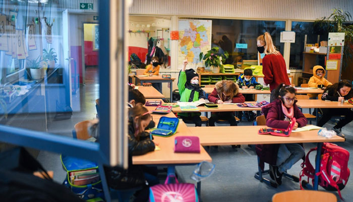 Children work with coats on inside a school in Germany that has open windows to improve ventilation. AFP
