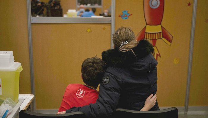 A child hugs his mother as he waits for his dose of the Pfizer-BioNTech vaccine in Montreal, Quebec. AFP