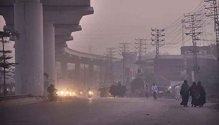 Motorists are on their way on GT Road Baghun Pura area during the morning hours as smog engulfs the area in provincial capital. Photo: Online/Sajid Rana