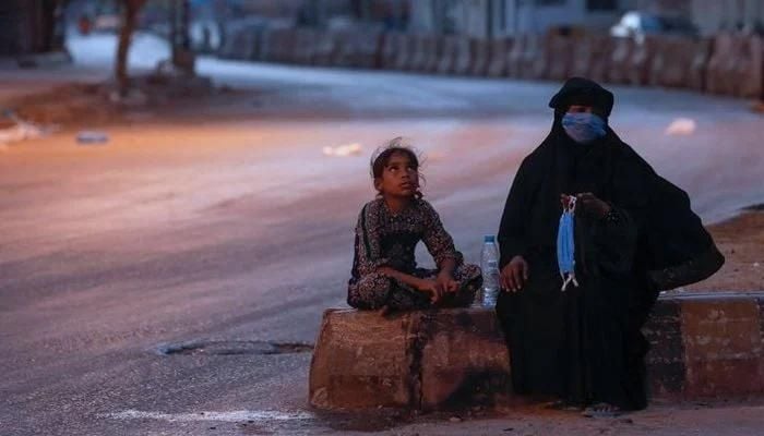 A woman and a girl sit on a deserted road on cold night in Karachi. Photo: Reuters