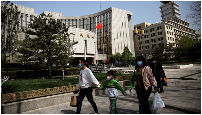 People wearing face masks walk past the headquarters of Chinese central bank Peoples Bank of China (PBOC), April 4, 2020. Photo: Reuters