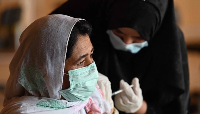 A woman wearing a mask being vaccinated against the novel coronavirus. Photo: Geo.tv/ file