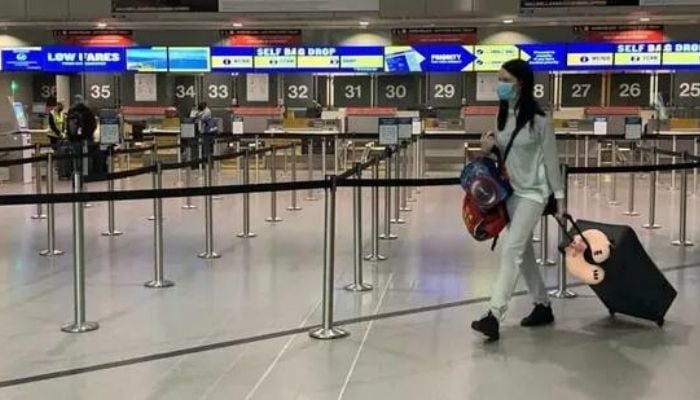 A passenger in the UK wearing a mask goes past the Ryanair check-in booths. Photo: Reuters