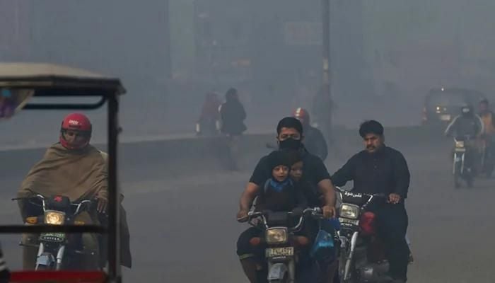 People commute along a street amid heavy smoggy conditions in Lahore. Photo: AFP