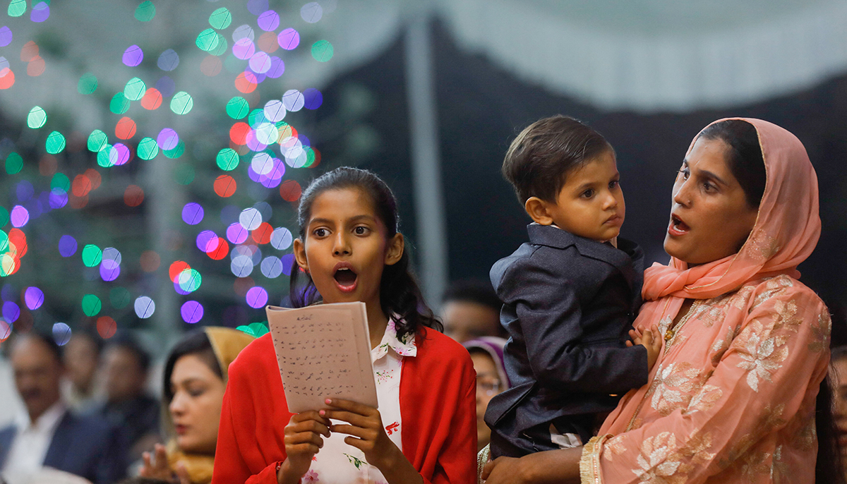 A girl sings along with her mother, who holds a boy in her arms, during a Christmas Eve service at St. Andrews Church in Karachi, Pakistan, December 24, 2021. — Reuters